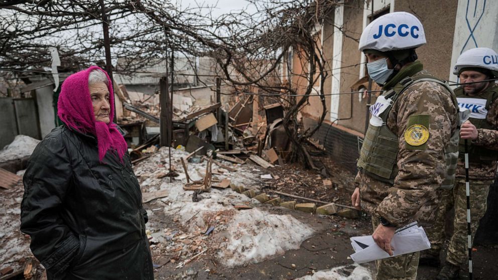 PHOTO: Valentyna Melnychenko listens to members of the Joint Center for Control and Coordination on ceasefire of the demarcation line (JCCC) surveying damage to her home from an artillery shell in Vrubivka, Luhansk region, eastern Ukraine, Feb. 17, 2022.