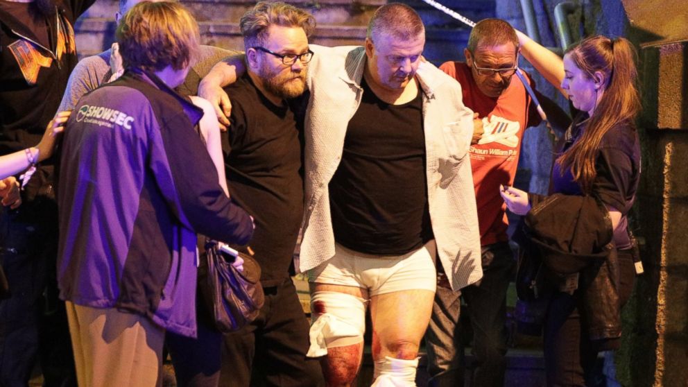 People aid an injured man near the Manchester Arena after reports of an explosion, May 22, 2017.
