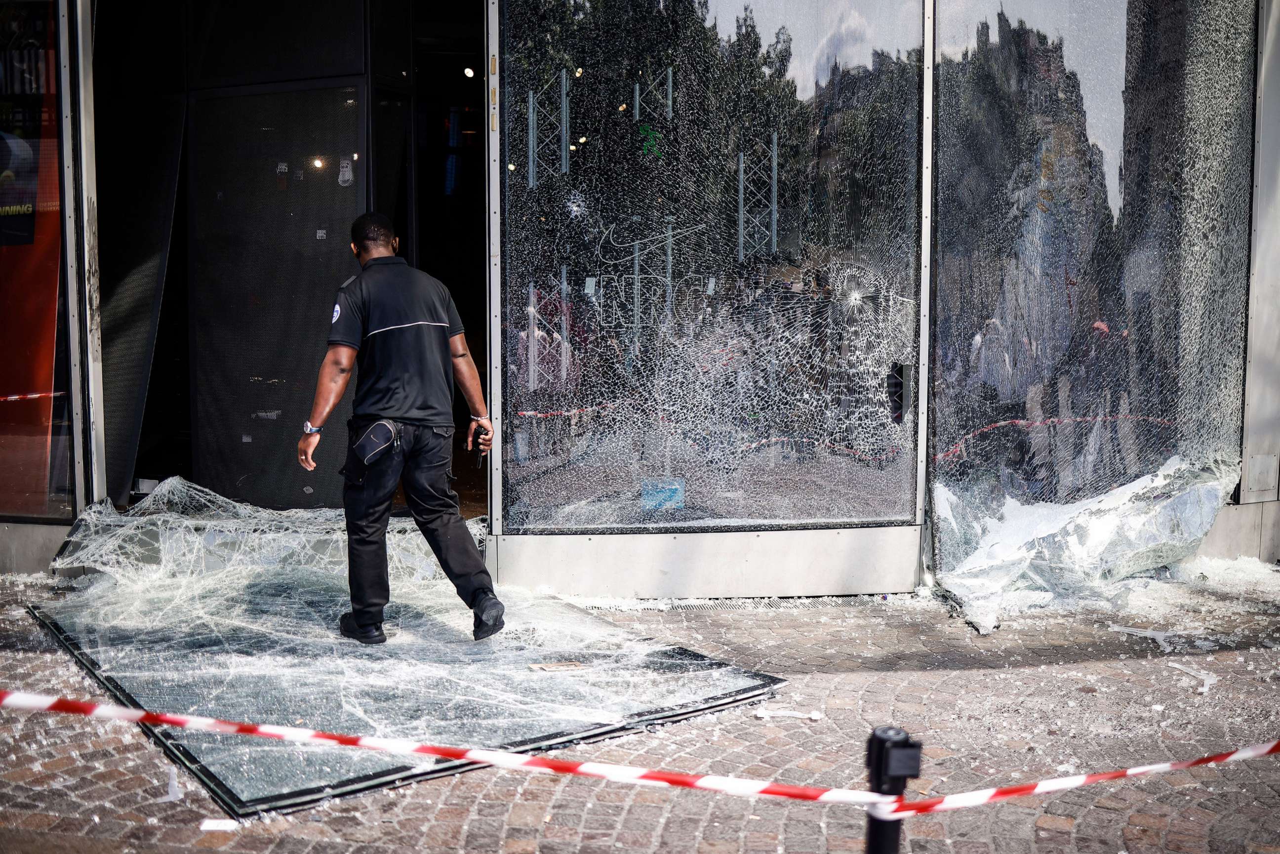 PHOTO: A security guard walks past a broken Nike store front window following riots in Paris, on June 30, 2023.
