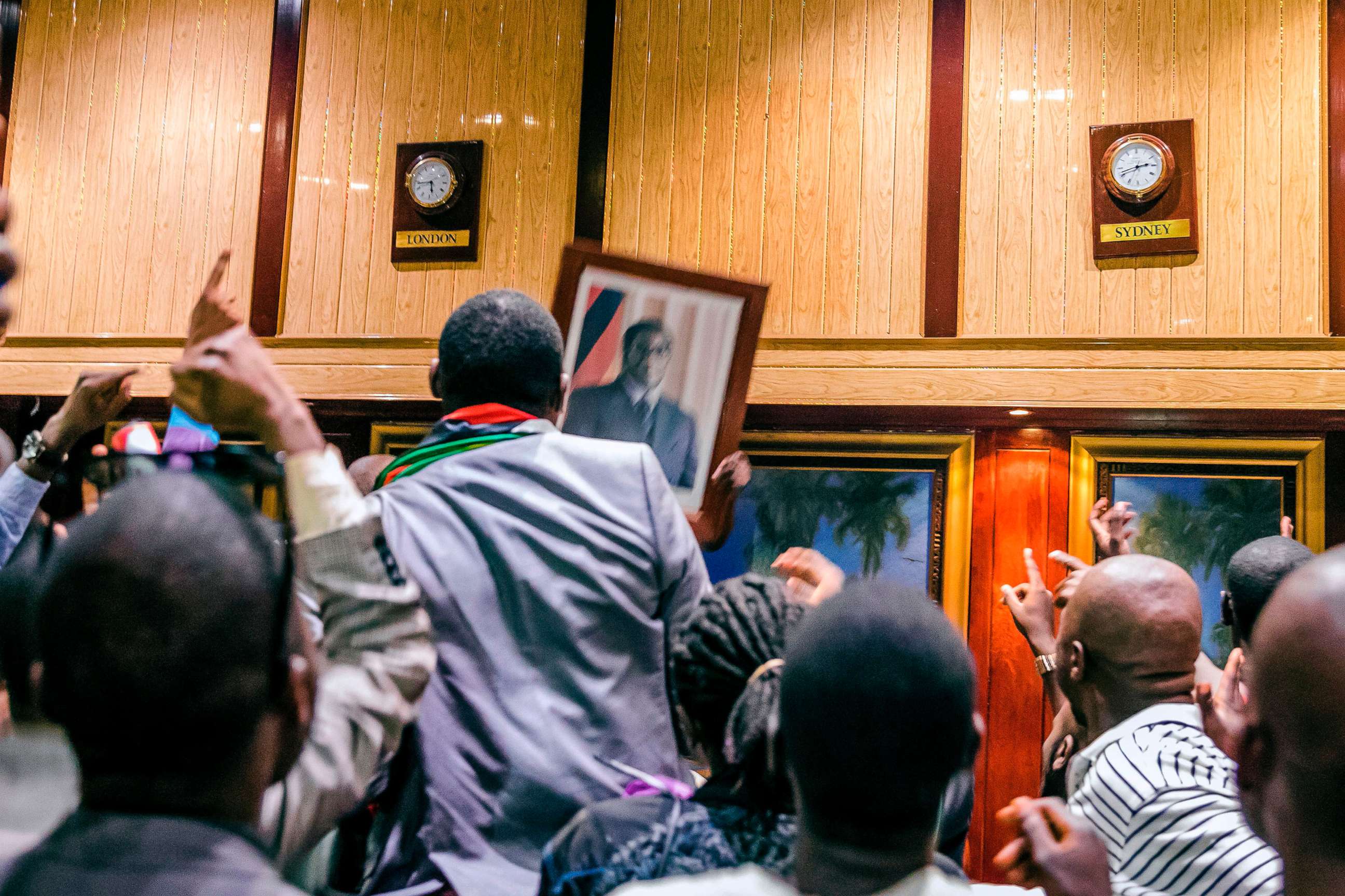 PHOTO: People remove, from the wall at the International Conference center, where parliament had their sitting, the portrait of former Zimbabwean President Robert Mugabe after his resignation on Nov. 21, 2017 in Harare.