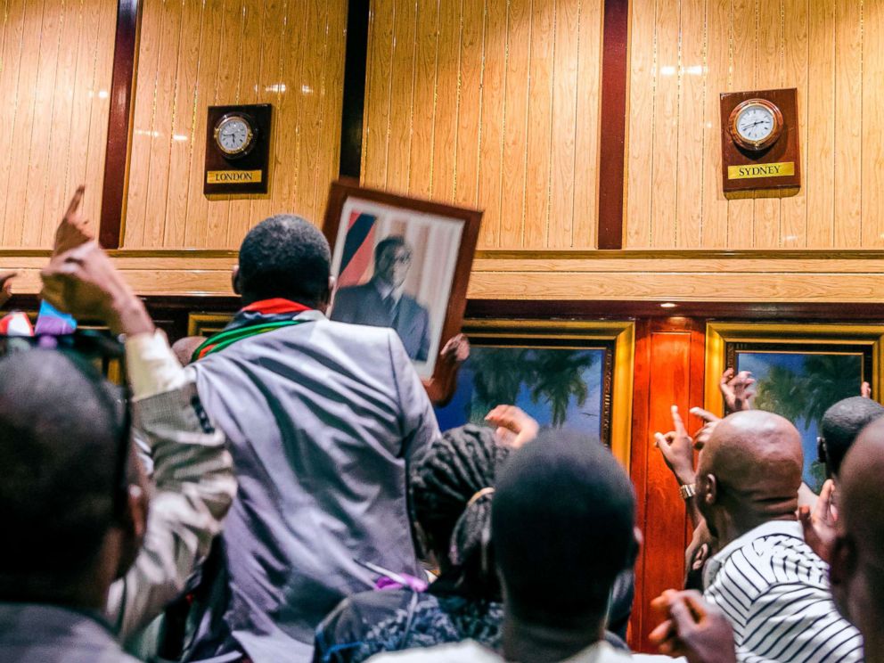 PHOTO: People remove, from the wall at the International Conference center, where parliament had their sitting, the portrait of former Zimbabwean President Robert Mugabe after his resignation on Nov. 21, 2017 in Harare.