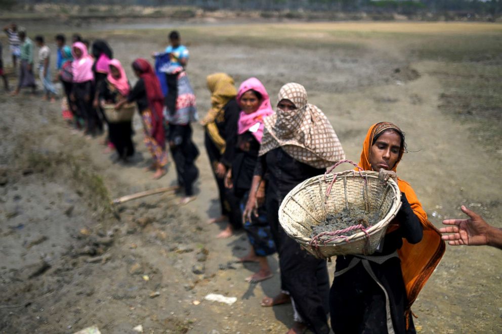 PHOTO: Rohingya refugee women carry baskets of dried out mud from the riverbed to help raise the ground level of the camp in preparation for monsoon season in Shamlapur refugee camp in Cox's Bazaar, Bangladesh, March 24, 2018.