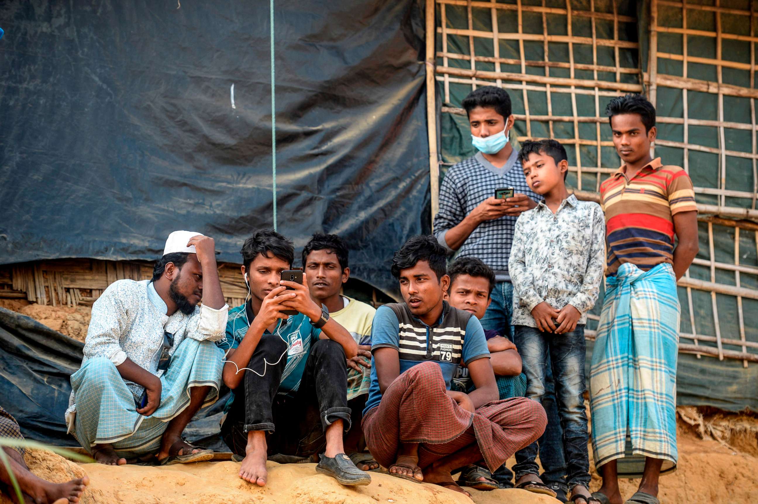 PHOTO: Rohingya refugees watch on a mobile phone Myanmar's State Counsellor Aung San Suu Kyi's at the U.N.'s International Court of Justice, on her hearing on the Rohingya genocide, in a refugee camp in Cox's Bazar in Bangladesh on Dec. 11, 2019.