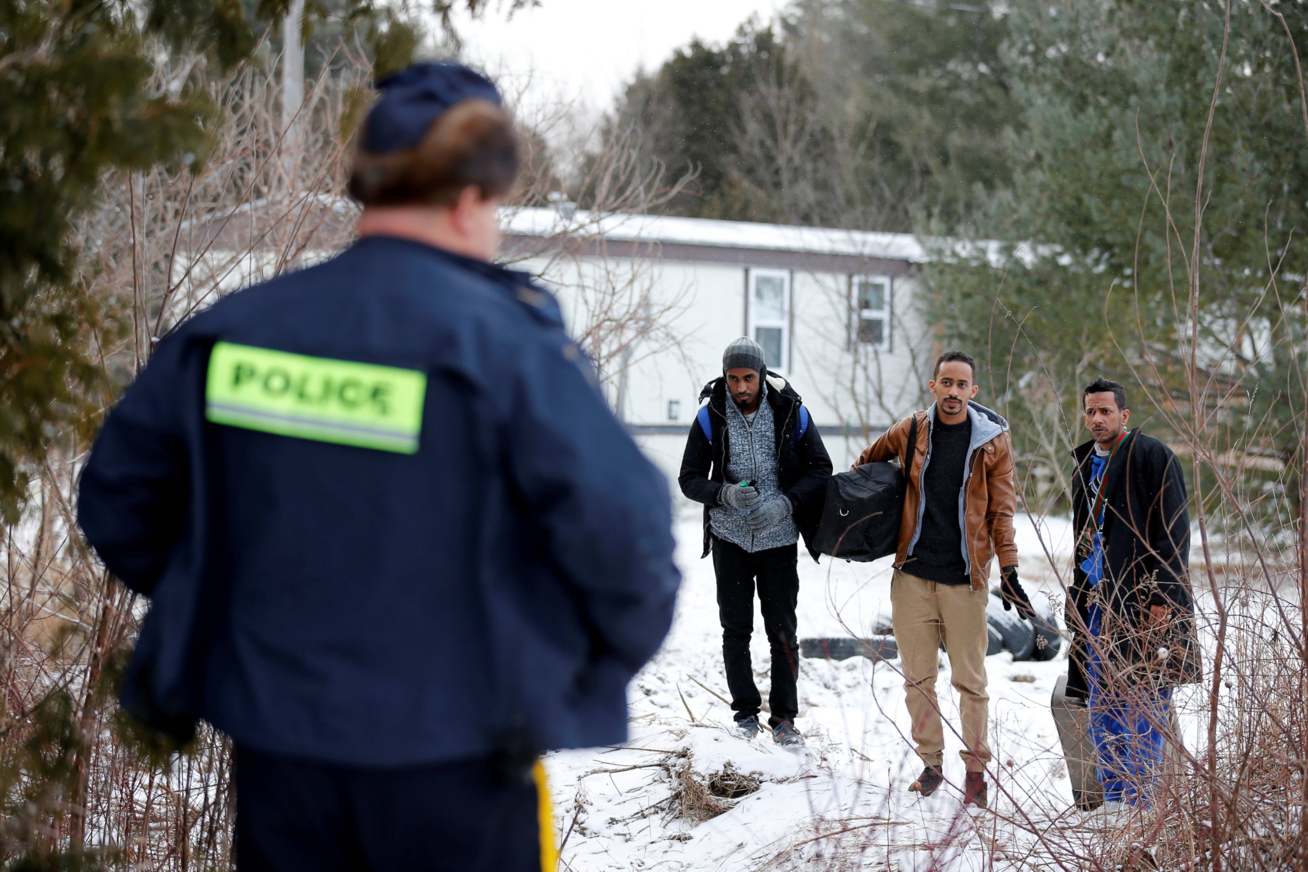 PHOTO: Three men who claimed to be from Sudan and were driven by taxi driver Curtis Seymour, are confronted by Royal Canadian Mounted Police (RCMP) as they prepare to cross illegally the U.S.-Canada border into Hemmingford, Quebec, Canada, March 4, 2017. 