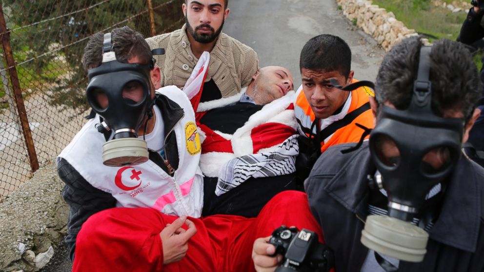 PHOTO: A Palestinian protester dressed in a Santa Claus costume is carried by medics after inhaling tear gas fired by Israeli troops during a demonstration near a Bethlehem checkpoint.