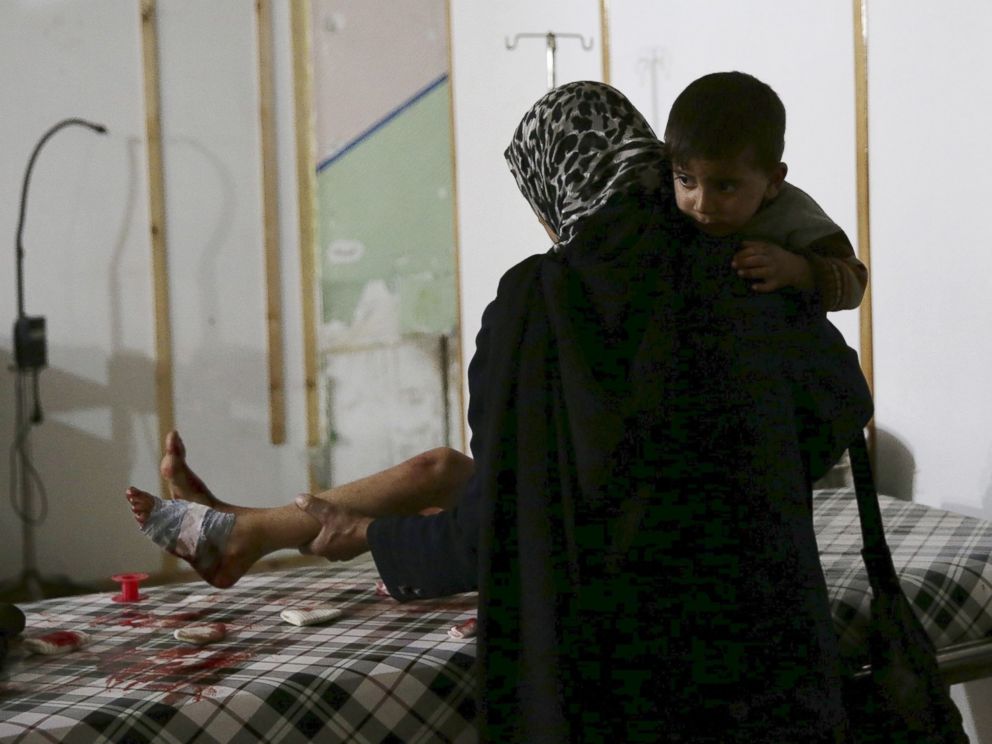 PHOTO: A woman carries a son while tending to the wounds of another son inside a field hospital in the Douma neighborhood of Eastern Ghouta, Syria, Nov. 19, 2015.