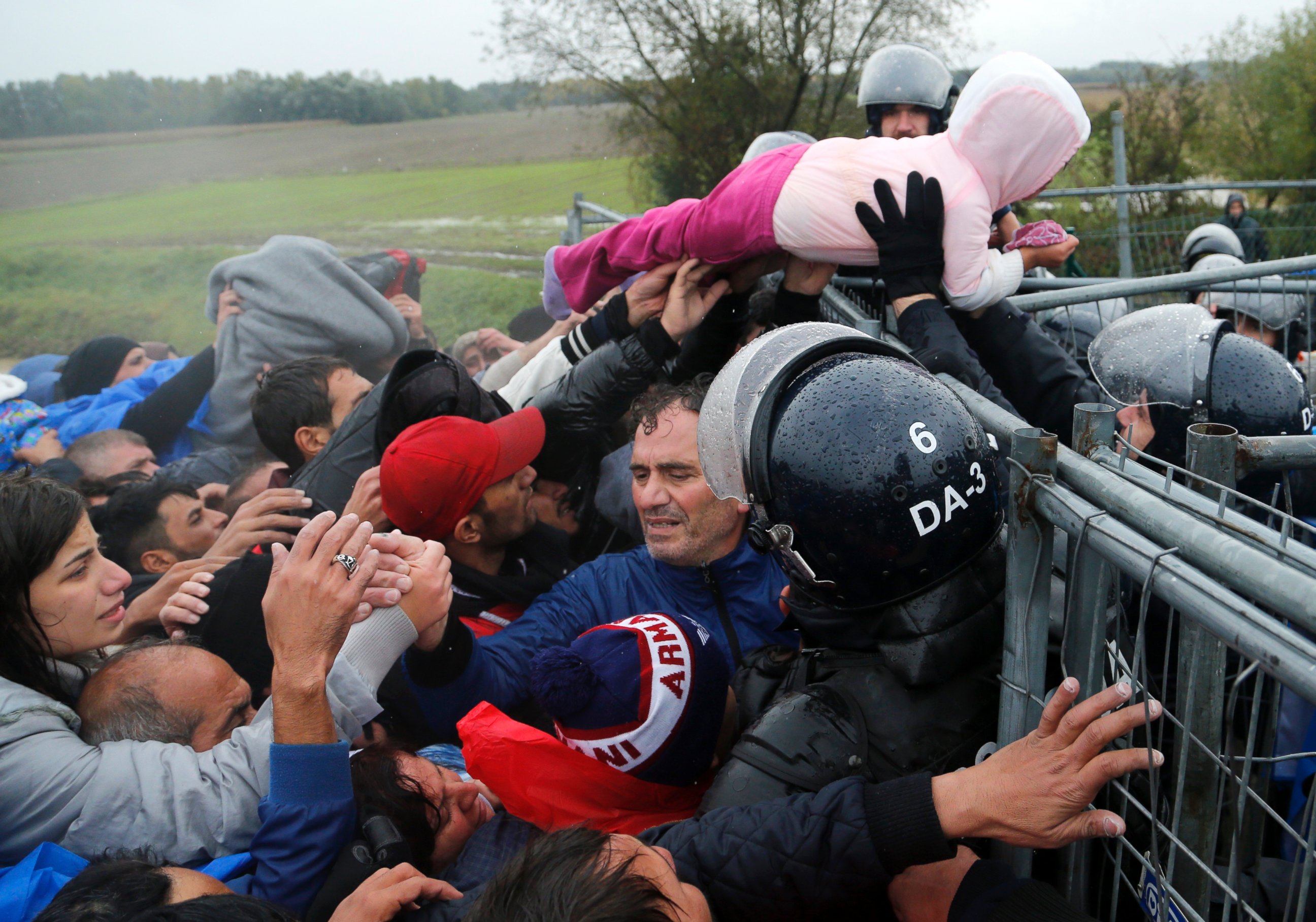 PHOTO: A child is lifted over a fence by Slovenian policemen as migrants attempt to cross the border near Trnovec, Croatia, Oct. 19, 2015.