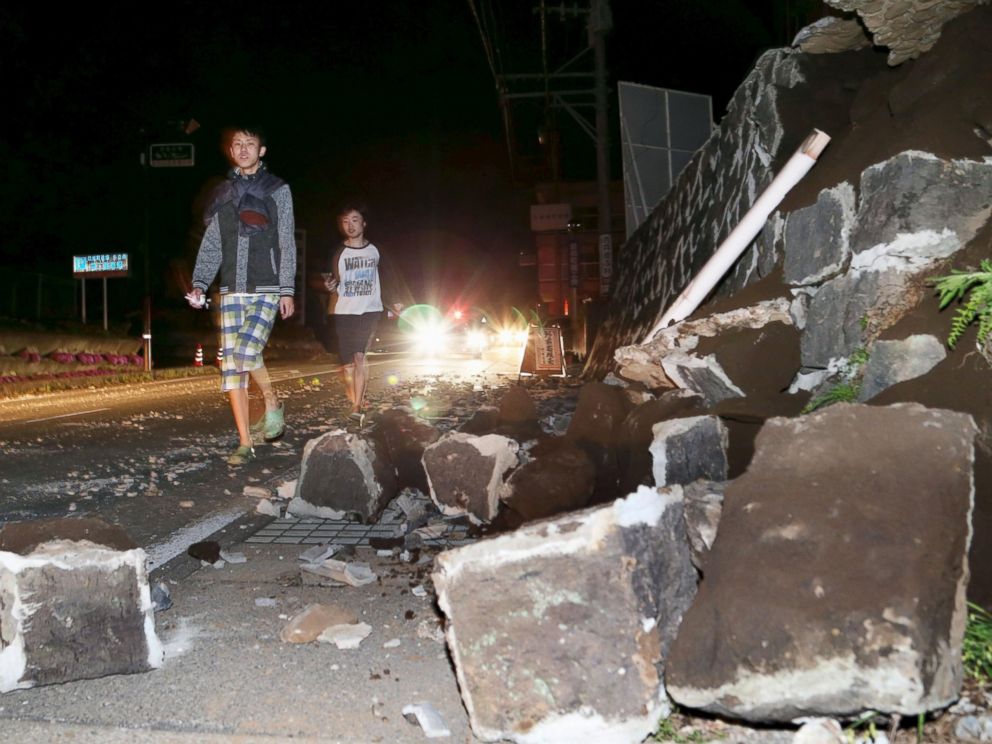 PHOTO: Local residents walk next to a collapsed wall after an earthquake in Mashiki town, Kumamoto prefecture, southern Japan, April 14, 2016.