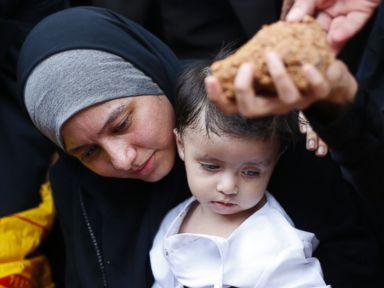 PHOTO: Asmaa Aljuned, holding her nine-month-old son Abderrahman, throws dirt into the grave of her husband, MH17 First Officer Ahmad Hakimi Hanapi, in Putrajaya August 22, 2014.