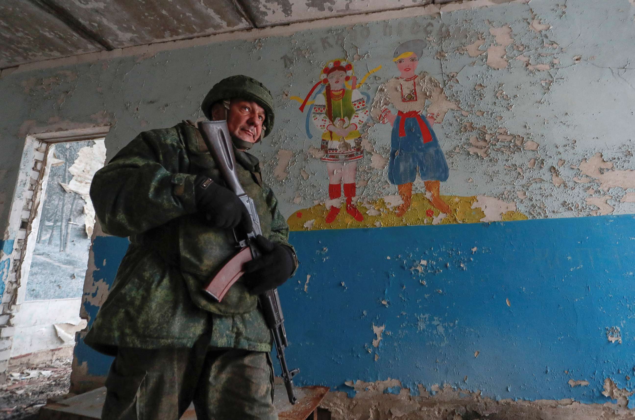 PHOTO: A militant of the self-proclaimed Luhansk People's Republic patrols the damaged building of a school located near the line of separation from the Ukrainian armed forces in the settlement of Molodizhne (Molodezhnoye), Ukraine February 17, 2022. 