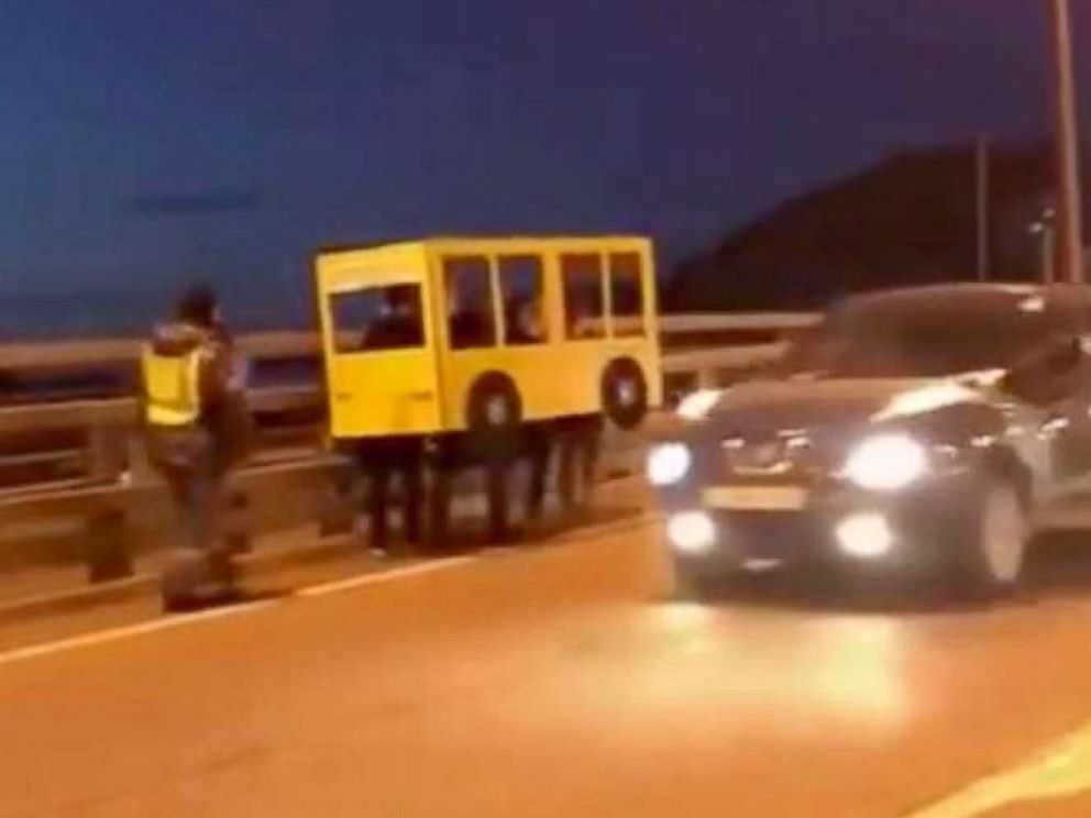 PHOTO: Une vidéo partagée largement sur les médias sociaux russes le 13 novembre 2018, montrait quatre personnes déguisées en autobus marchant sur le pont d'or à Vladivostok, en Russie.