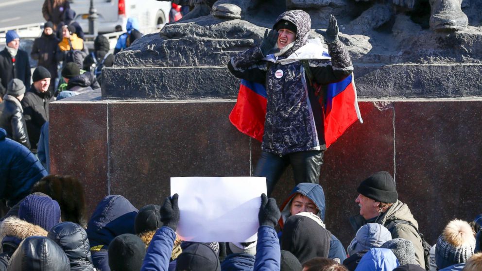 A demonstrator with a Russian national flag wrapped in his shoulders shouts slogans during a rally in Vladivostok, Russia, Jan. 28, 2018.