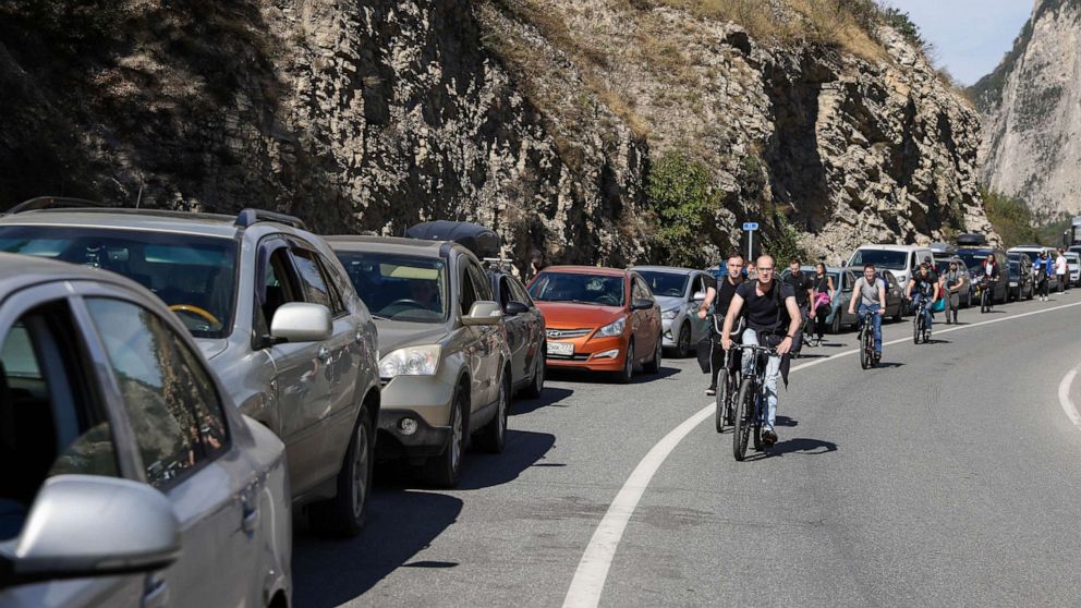 PHOTO: People ride bicycles along a queue of vehicles at the Verkhny Lars checkpoint in North Ossetia, Russia on the border to Georgia, on Sept. 27, 2022. Around 3.5 thousand cars are queueing at the checkpoint to cross the border from Russia to Georgia.