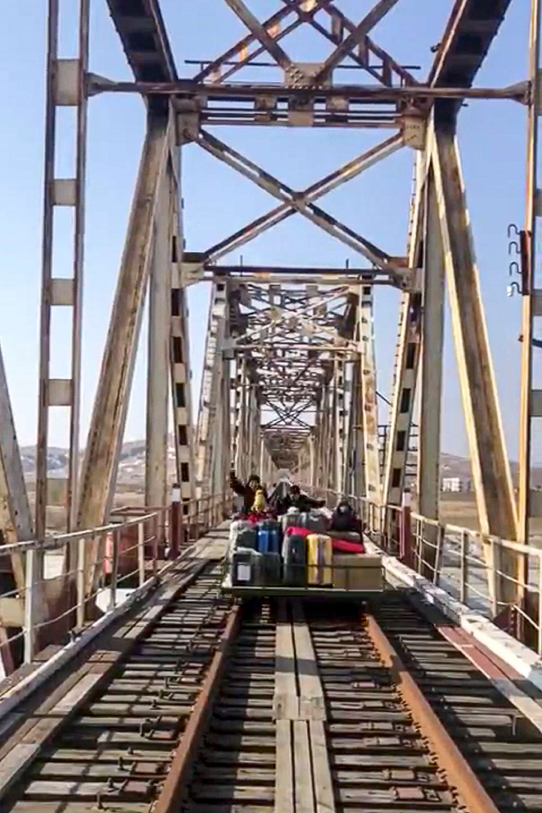 PHOTO: In this image taken from a video released by Russian Foreign Ministry Press Service, Feb. 25, 2021, a group of Russian diplomats push hand-pushed rail trolley with their children and suitcases crossing a railway bridge to the border with Russia.