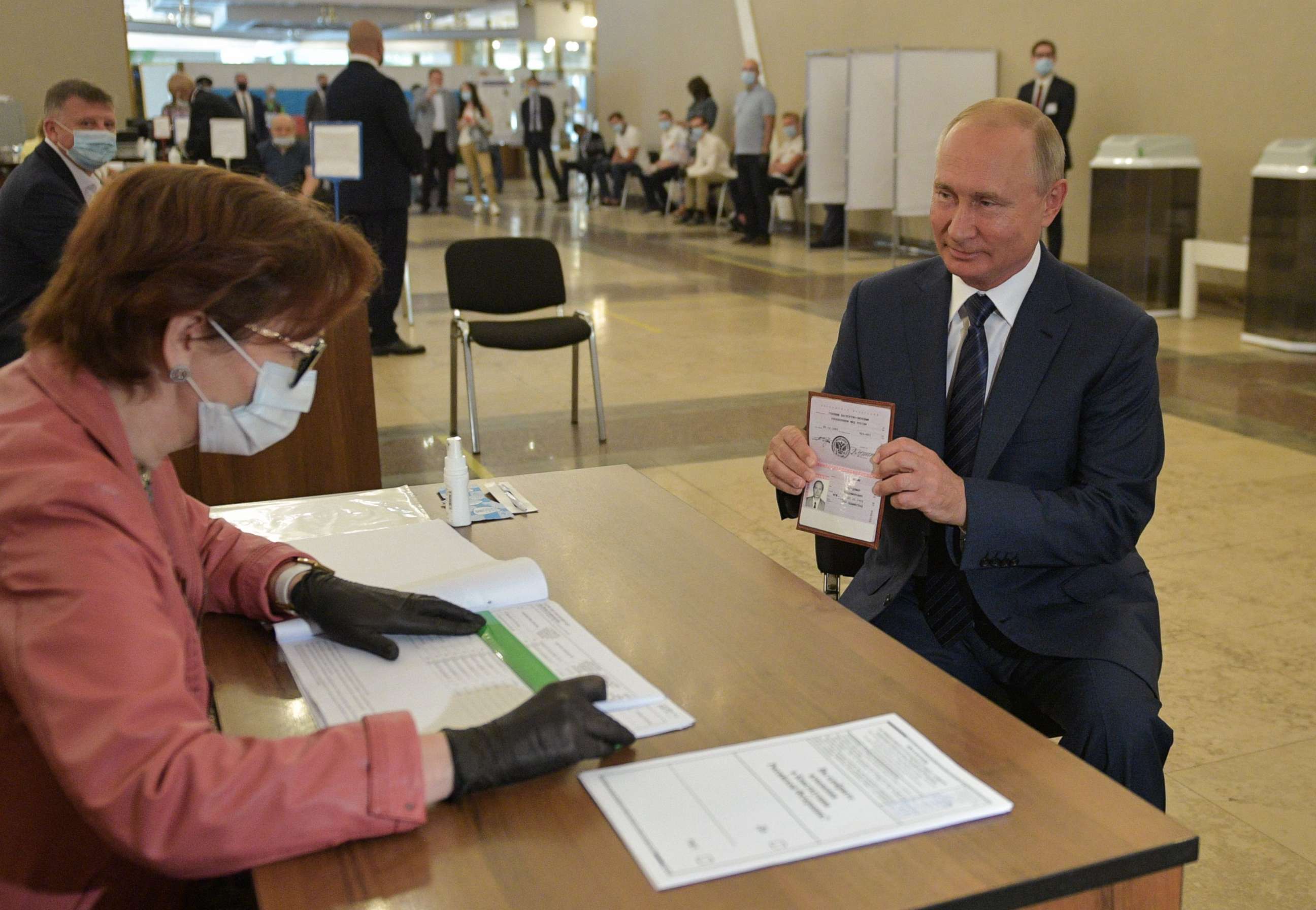 PHOTO: Russian President Vladimir Putin shows his passport to a member of a local electoral commission as he arrives to cast his ballot in a nationwide vote on constitutional reforms at a polling station in Moscow on July 1, 2020.