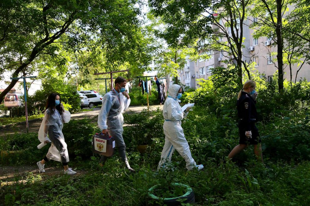 PHOTO: Members of a local electoral commission walk with a mobile ballot box in a yard as they visit voters at their homes during a nationwide vote on constitutional reforms in the far eastern city of Vladivostok on July 1, 2020.