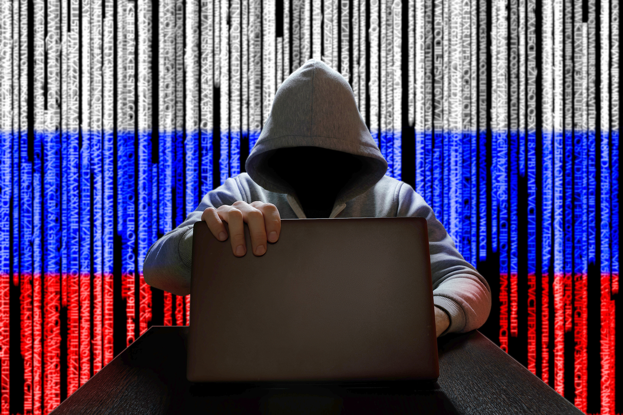 PHOTO: A hooded figure works on a laptop with a Russian Flag digital code backdrop in an undated stock image.