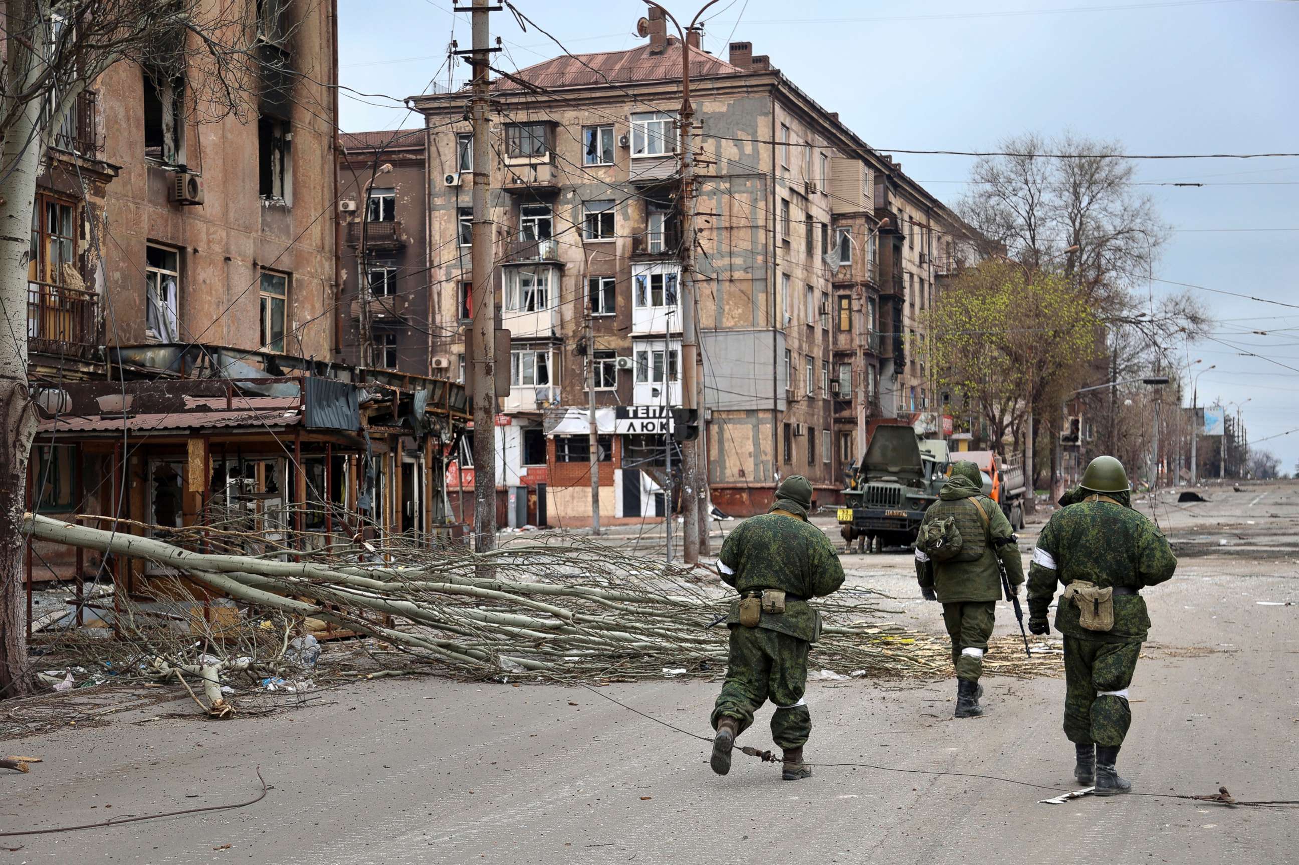 PHOTO: Servicemen of Donetsk People's Republic militia walk past damaged apartment buildings near the Illich Iron & Steel Works Metallurgical Plant, in an area controlled by Russian-backed separatist forces in Mariupol, Ukraine, April 16, 2022.
