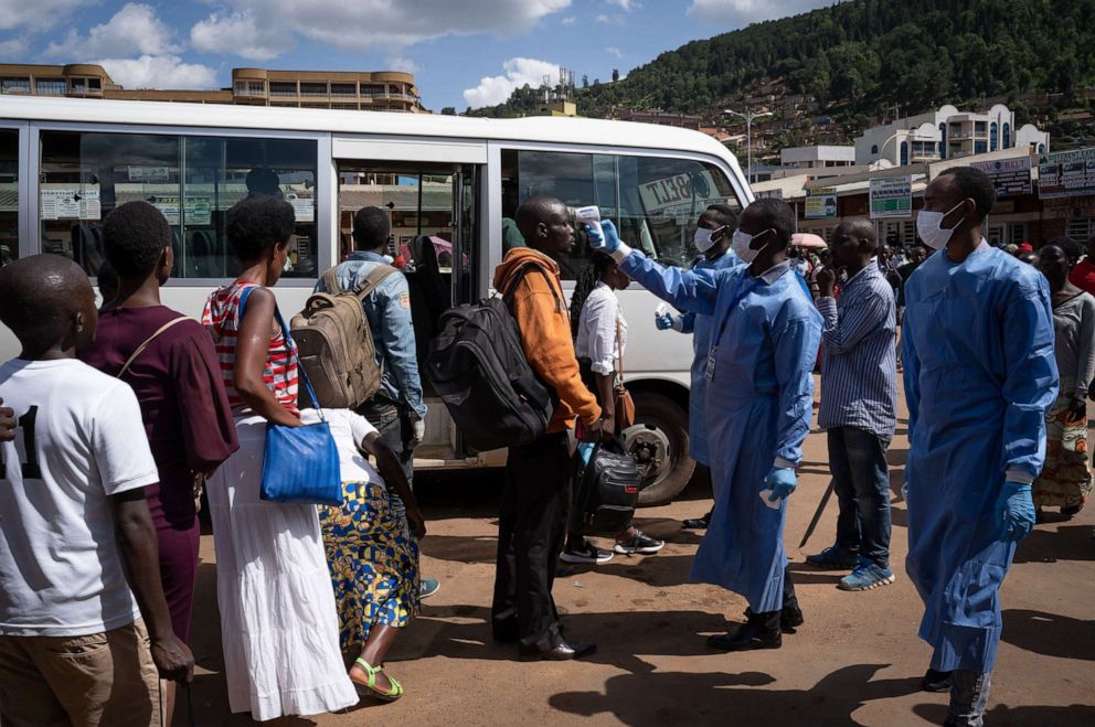 In this March 22, 2020, file photo, a staff member of the Rwanda Biomedical Center (RBC) screens passengers at a bus station after the government suspended all unnecessary movements for two weeks to curb the spread of COVID-19 in Kigali, Rwanda.Simon Wohlfahrt/AFP via Getty Images, FILE