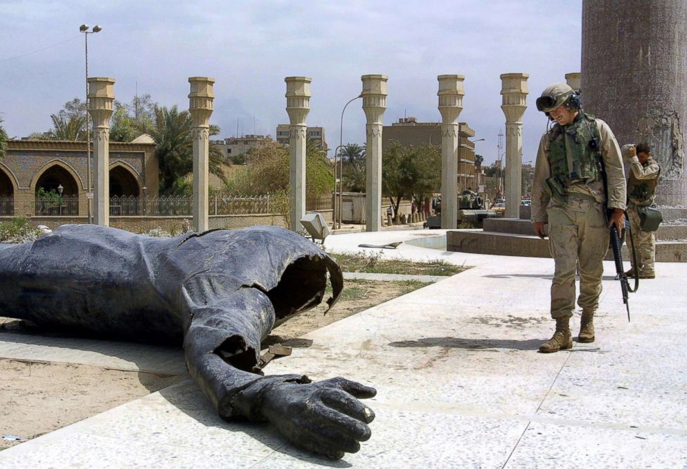 PHOTO: US Marines walk pass a dismounted statue of Saddam Hussein on Baghdad's al-Fardous square, April 10, 2003.