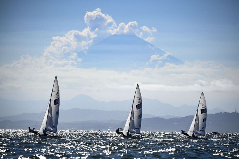 PHOTO: Japan's Ai Yoshida and Miho Yoshioka, Britain's Hannah Mills and Eilidh Mcintyre and France's Aloise Retornaz and Camille Lecointre sail past Mount Fuji during the women's two-person dinghy 470 medal race in Fujisawa, Japan, on Aug. 4, 2021.