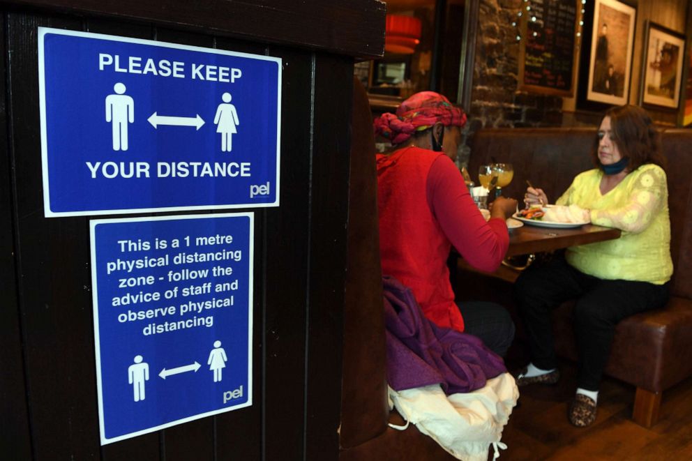 PHOTO: A sign outlining social distancing is displayed near customers in Jackson's Bar in the city centre of Glasgow, Scotland on Oct. 8, 2020.