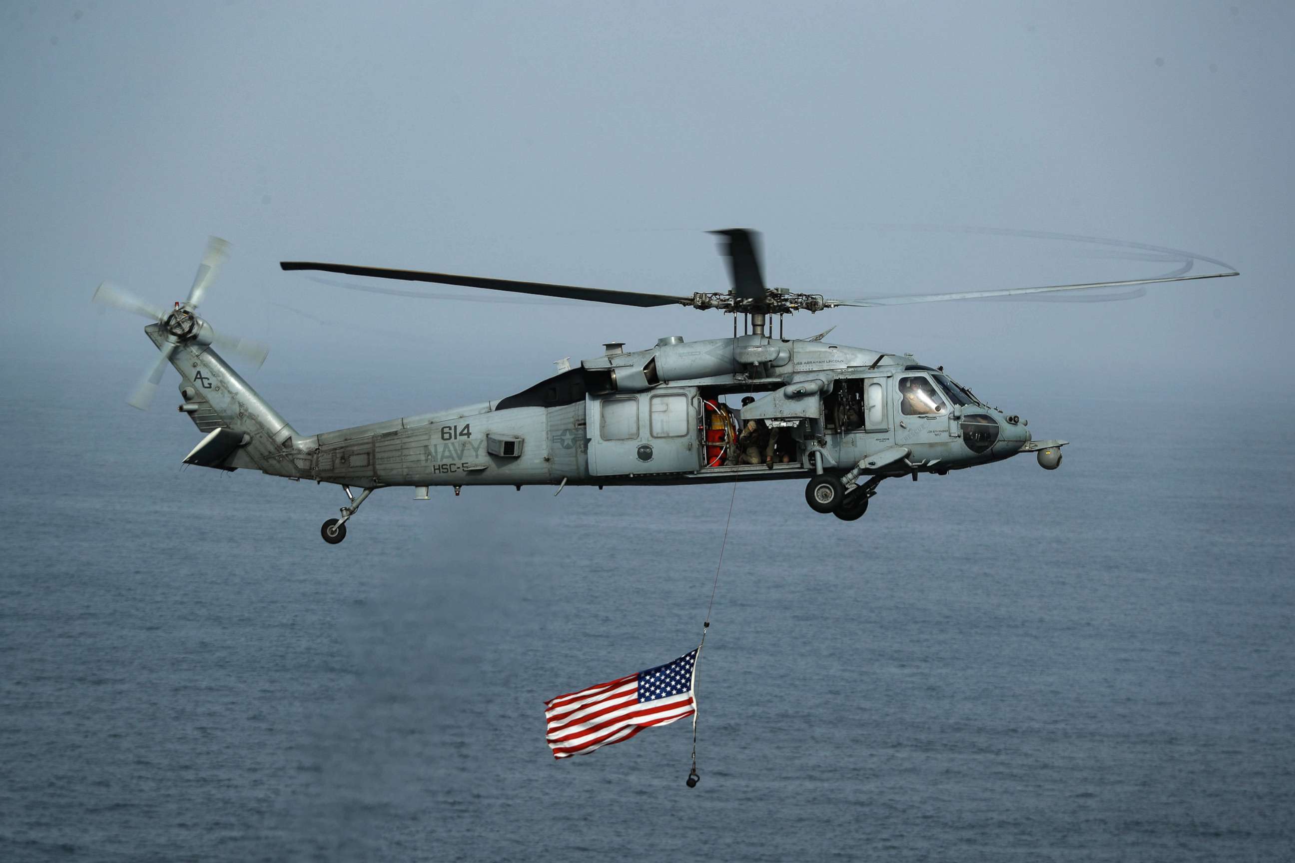 PHOTO: An MH-60S Sea Hawk helicopter flies over the Nimitz-class aircraft carrier USS Abraham Lincoln, July 4, 2019.