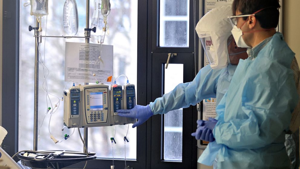 PHOTO: Nurse Jason Doff and Dr. James Darnton, right, check on a patient in the acute care COVID-19 unit at Harborview Medical Center on Jan. 21, 2022, in Seattle.