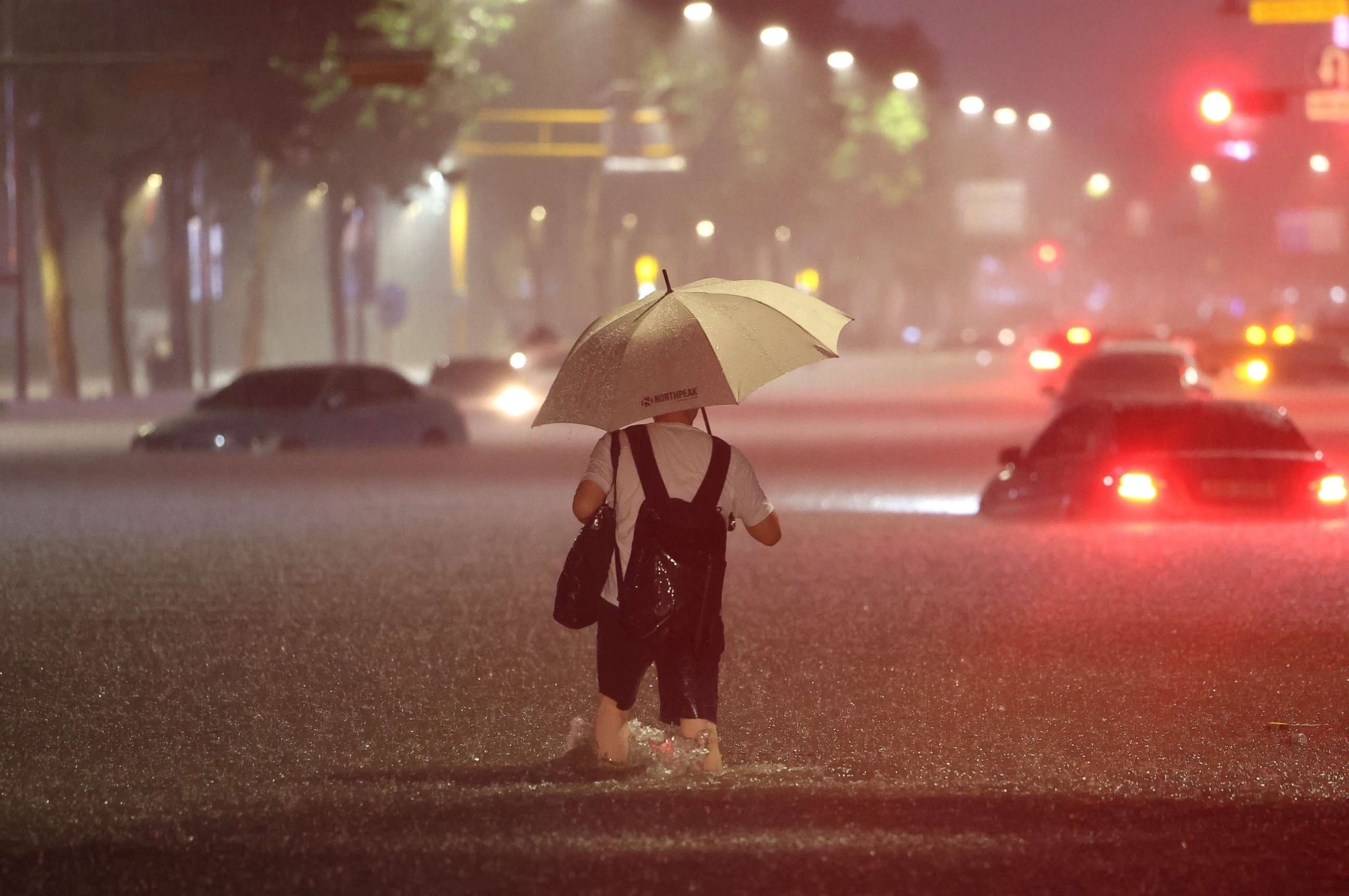 PHOTO: A man wades alongside submerged cars in a street during heavy rainfall in the Gangnam district of Seoul, South Korea, on Aug. 8, 2022.