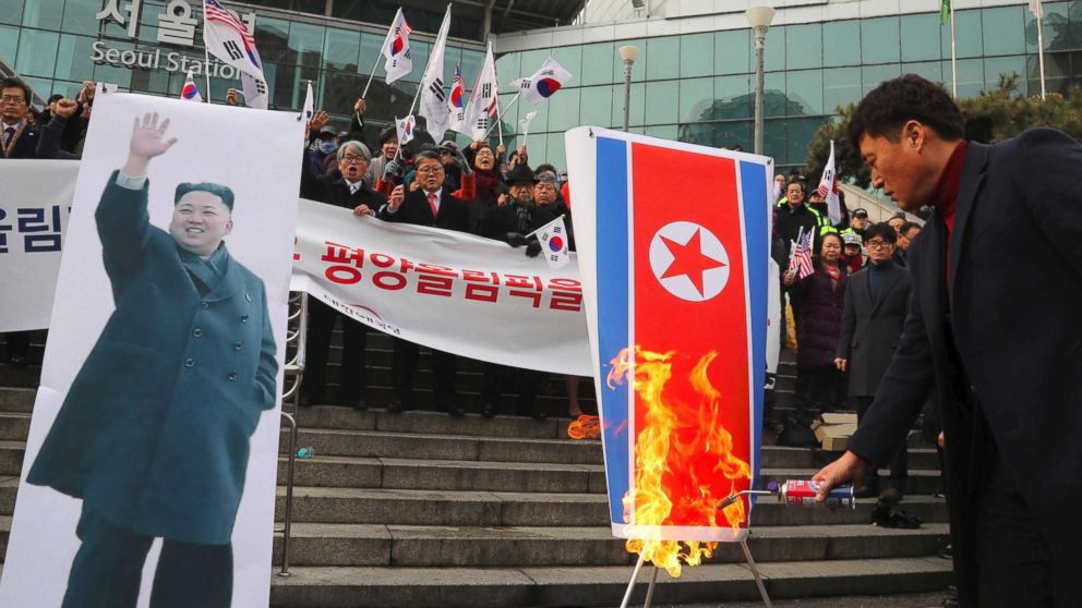 South Korean protesters burn a North Korean flag, right, and a picture ,left, of North Korean leader Kim Jong-Un during an anti-North Korea rally outside Seoul station in Seoul, Jan. 22, 2018, as a North Korean delegation arrives at the station.