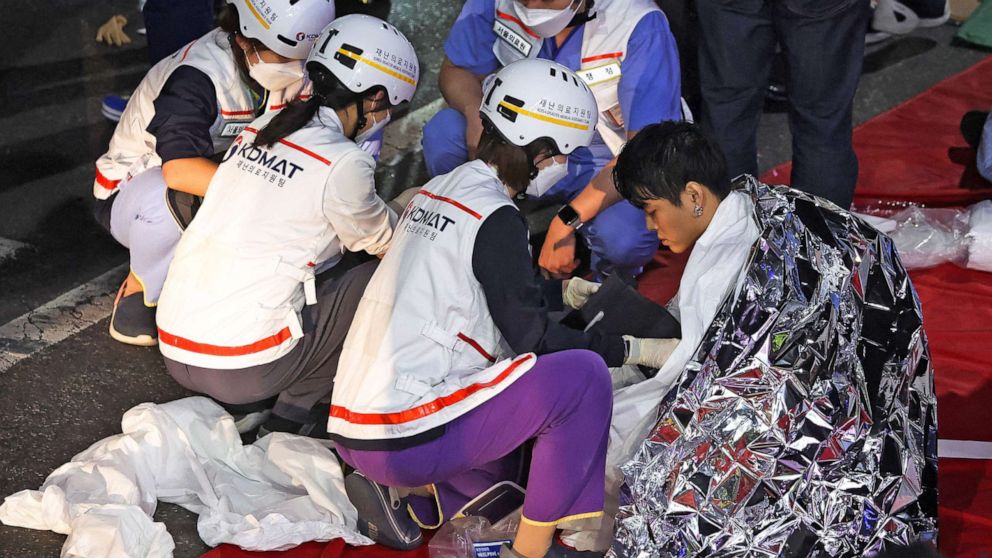 写真: 2022 年 10 月 30 日、韓国のソウルで開催されたハロウィーン フェスティバルで、数十人が押しつぶされて負傷した現場で、救助隊のメンバーから医療援助を受ける男性。 