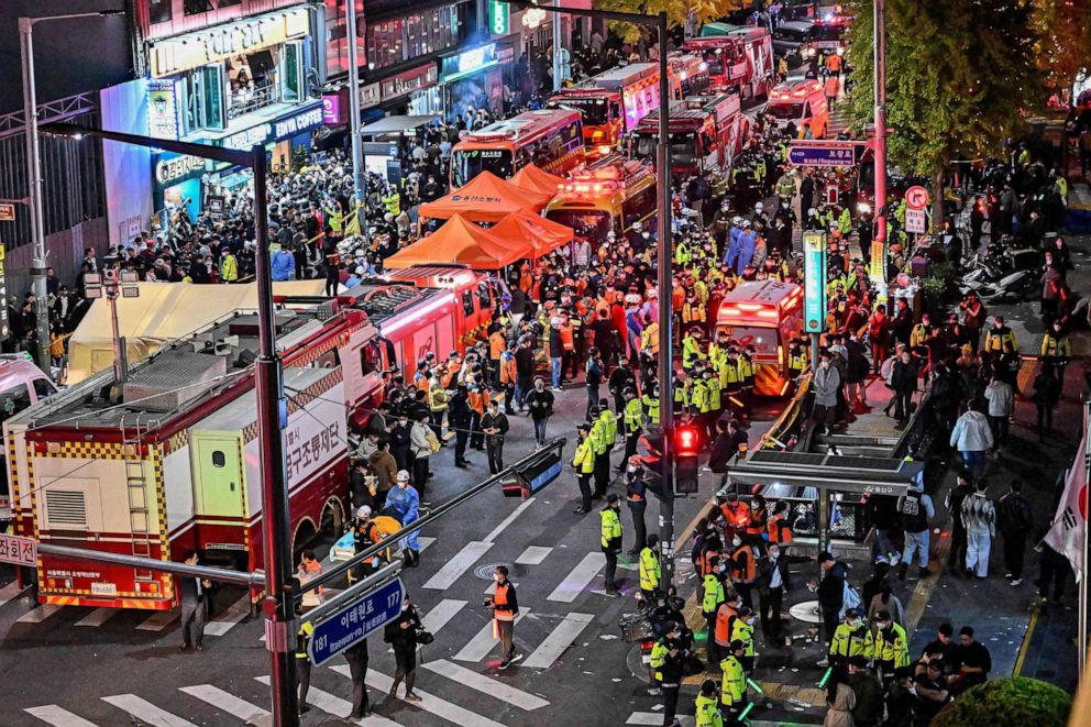 FOTO: Osoby postronne, policjanci i personel medyczny gromadzą się po ludziach zgromadzonych na wąskich uliczkach w dzielnicy Itaewon 30 października 2022 r. w Seulu w Korei Południowej.