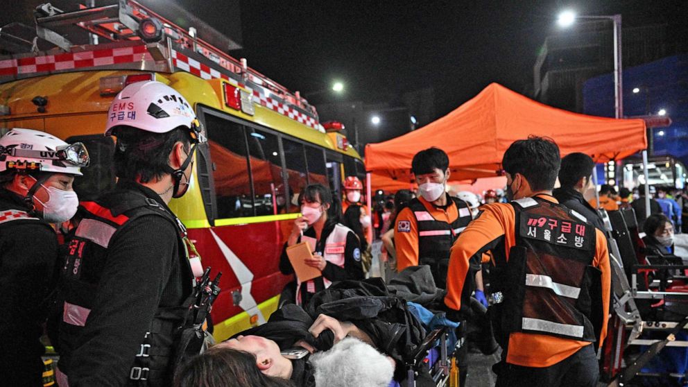 写真: 医療スタッフは、2022 年 10 月 30 日、韓国のソウルで、ハロウィーンを祝うために市内の梨泰院地区の狭い通りに群がった後、数十人が負傷した後、担架で人の世話をします。