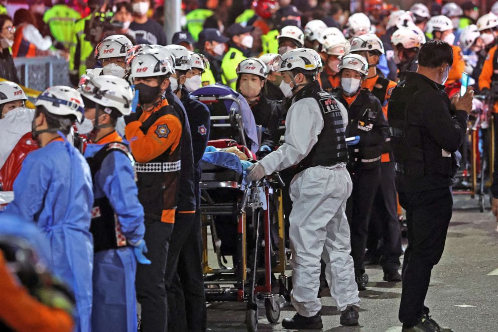 写真: 救助隊員は、2022 年 10 月 30 日、韓国のソウルでのハロウィーン フェスティバル中に押し寄せて数十人が負傷した現場でストレッチャーを持って待機しています。