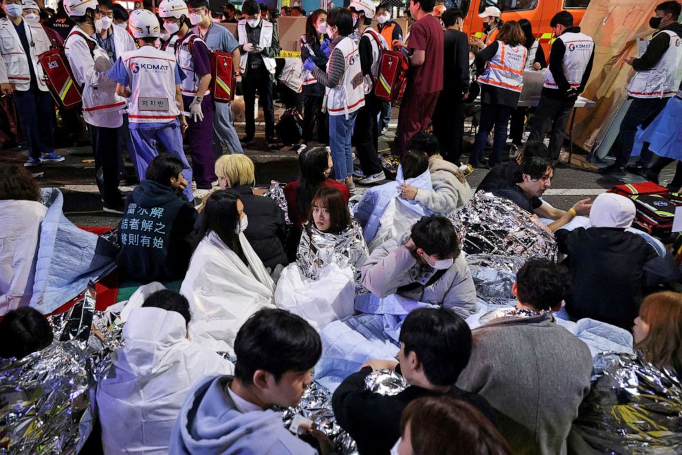 ZDJĘCIE: Ludzie siedzą na ulicy po uratowaniu w miejscu, w którym dziesiątki osób zostało rannych w panice podczas festiwalu Halloween w Seulu w Korei Południowej, 30 października 2022 r.