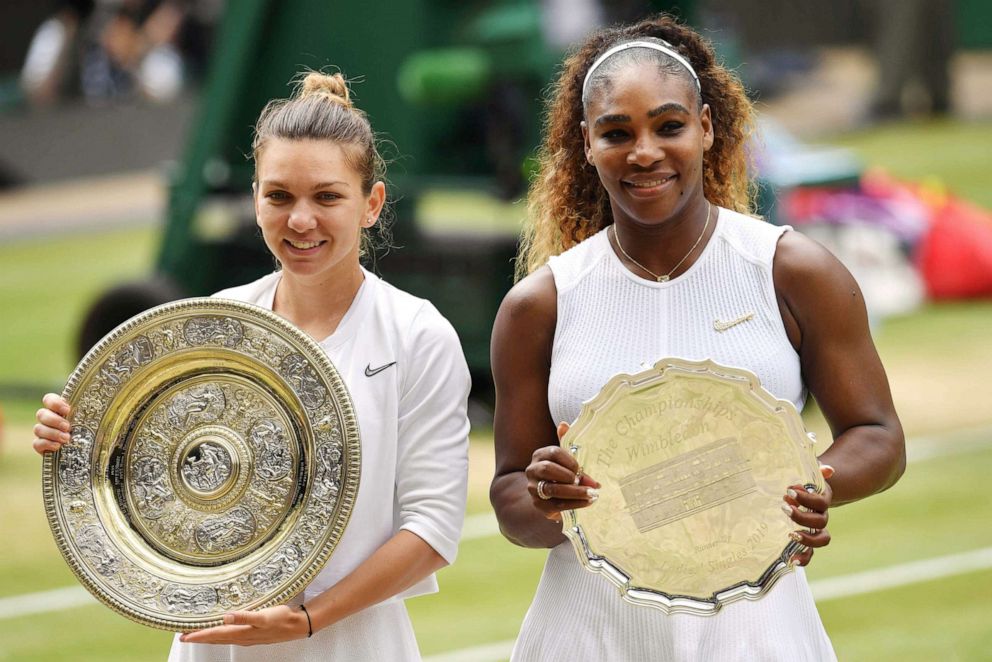 PHOTO:Romania's Simona Halep poses with the Venus Rosewater Dish trophy and Serena Williams poses with the runners up trophy after Halep won their women's singles final on day twelve of the 2019 Wimbledon Championships in Wimbledon, London, July 13, 2019.