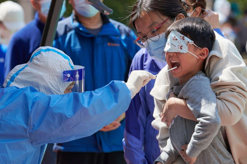 PHOTO: A child receives a swab test for the COVID-19 in a compound in Shanghai on April 17, 2022.