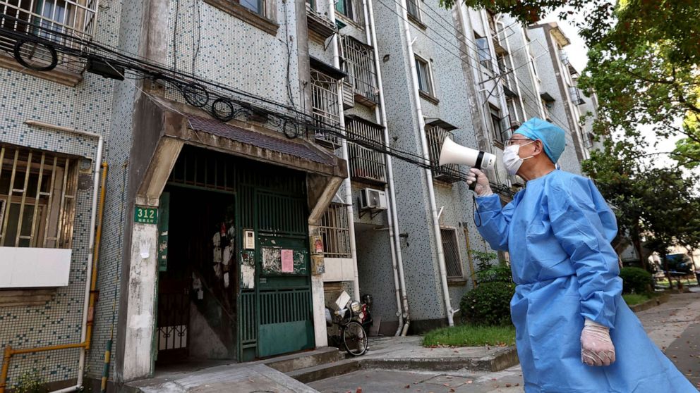 PHOTO: In this photo released by China's Xinhua News Agency, a volunteer uses a megaphone to talk to residents at an apartment building in Shanghai, China, Tuesday, April 12, 2022.