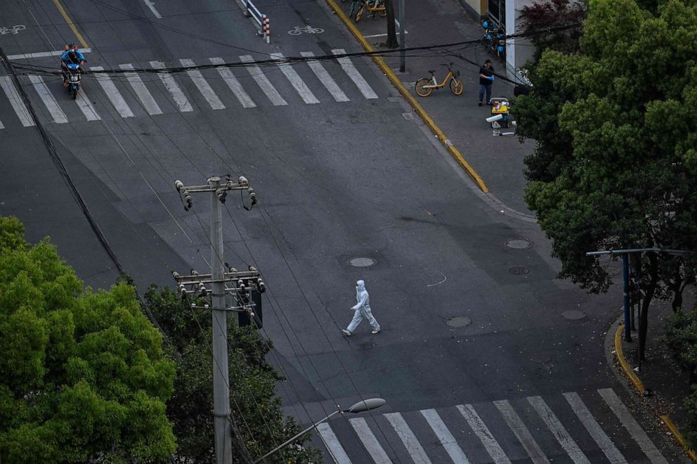PHOTO: A worker wearing personal protective equipment  walks on a street during a COVID-19 lockdown in the Jing'an district in Shanghai, April 12, 2022.