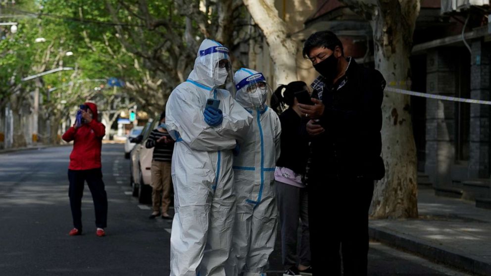 PHOTO: Workers in a protective suits direct residents lining up for nucleic acid test during lockdown amid COVID-19 pandemic, in Shanghai, April 17, 2022.