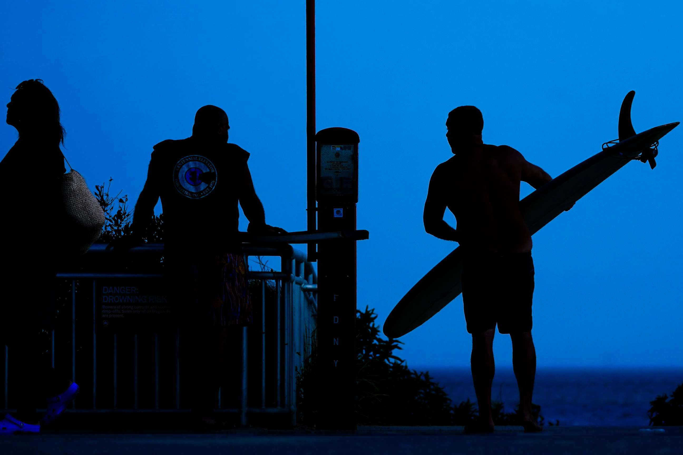 PHOTO: A surfer arrives at Rockaway Beach, July 19, 2022, in Queens, New York.