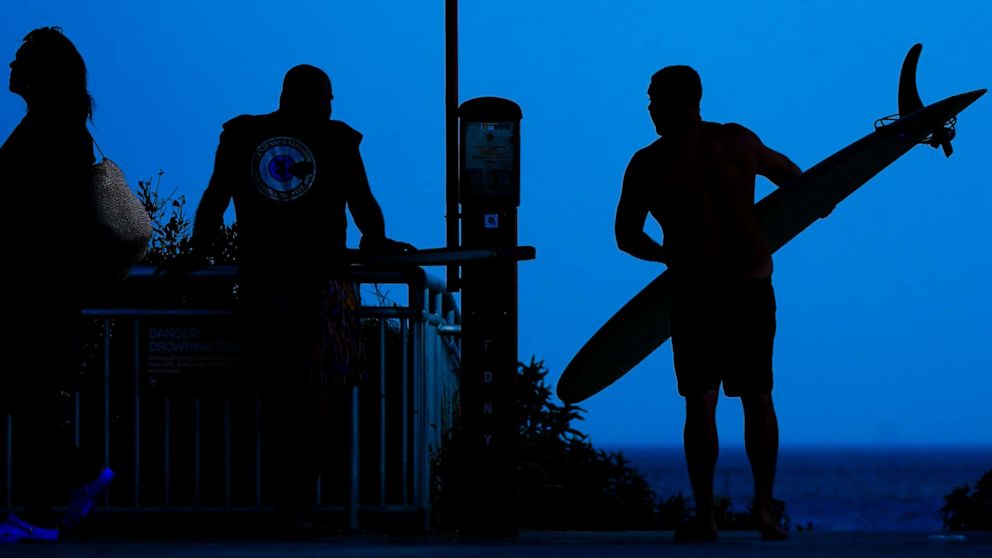PHOTO: A surfer arrives at Rockaway Beach, July 19, 2022, in Queens, New York.