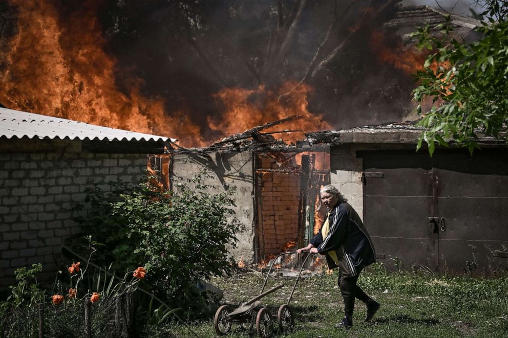 PHOTO: An elderly woman walks away from a burning house in Lysytsansk, a city located in the eastern Ukrainian region of Donbas, on May 30, 2022.