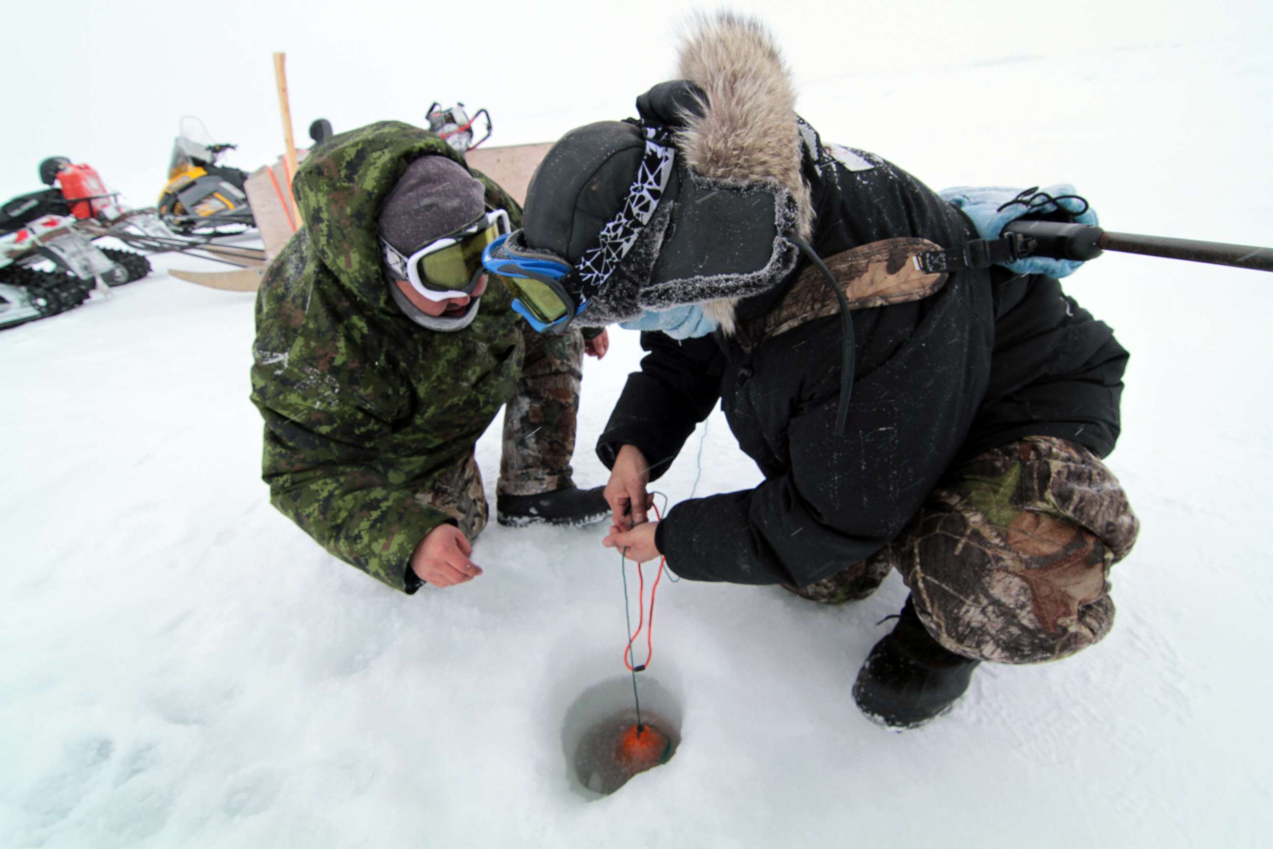 PHOTO: Hunters involved on Community Driven Research with AES take a water sample through the sea ice near Kuujjuaraapik.
