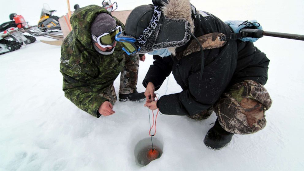 PHOTO: Hunters involved on Community Driven Research with AES take a water sample through the sea ice near Kuujjuaraapik.