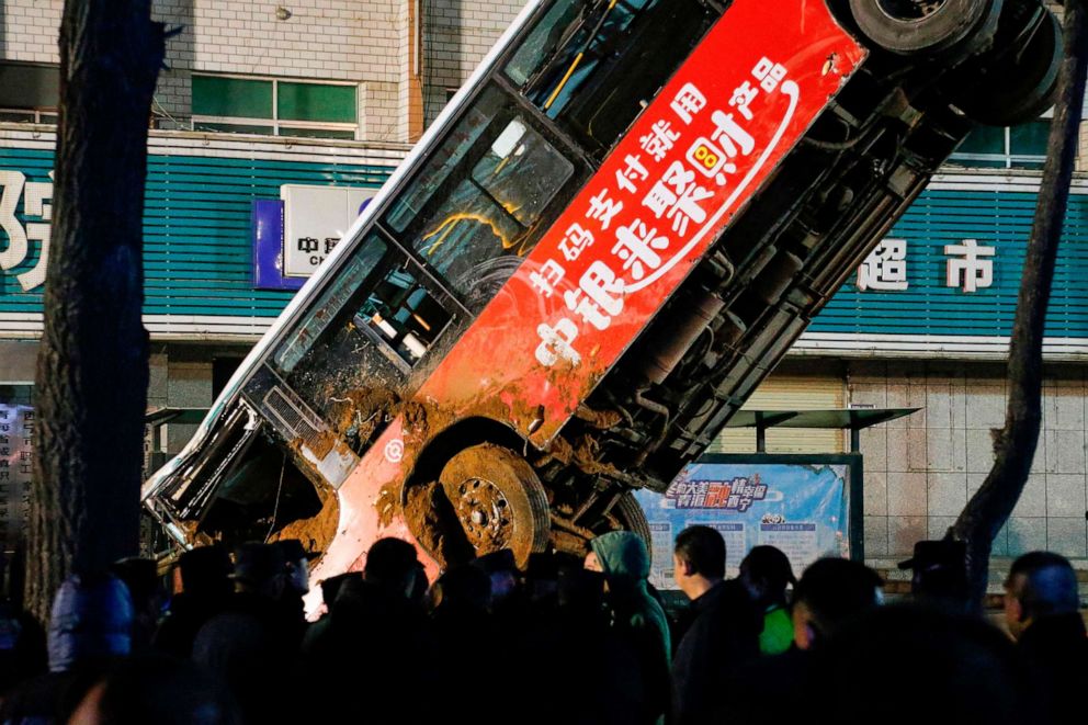 PHOTO: Rescuers watch as a bus is lifted out after a road collapse in Xining in China.