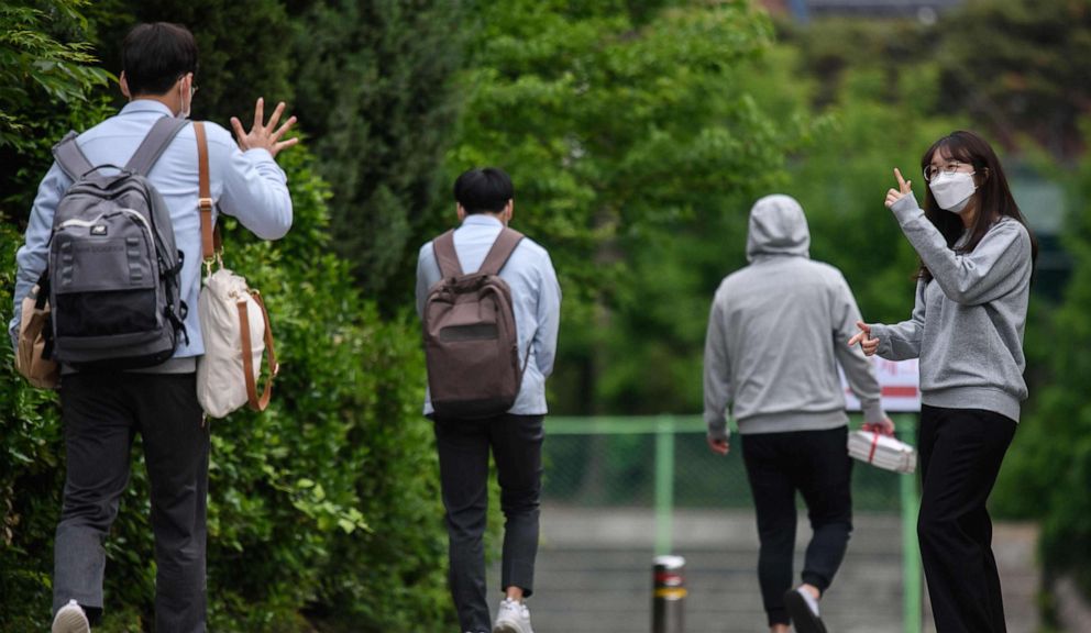 PHOTO: A staff member greets students as they arrive at Kyungbock High School in Seoul on May 20, 2020.
