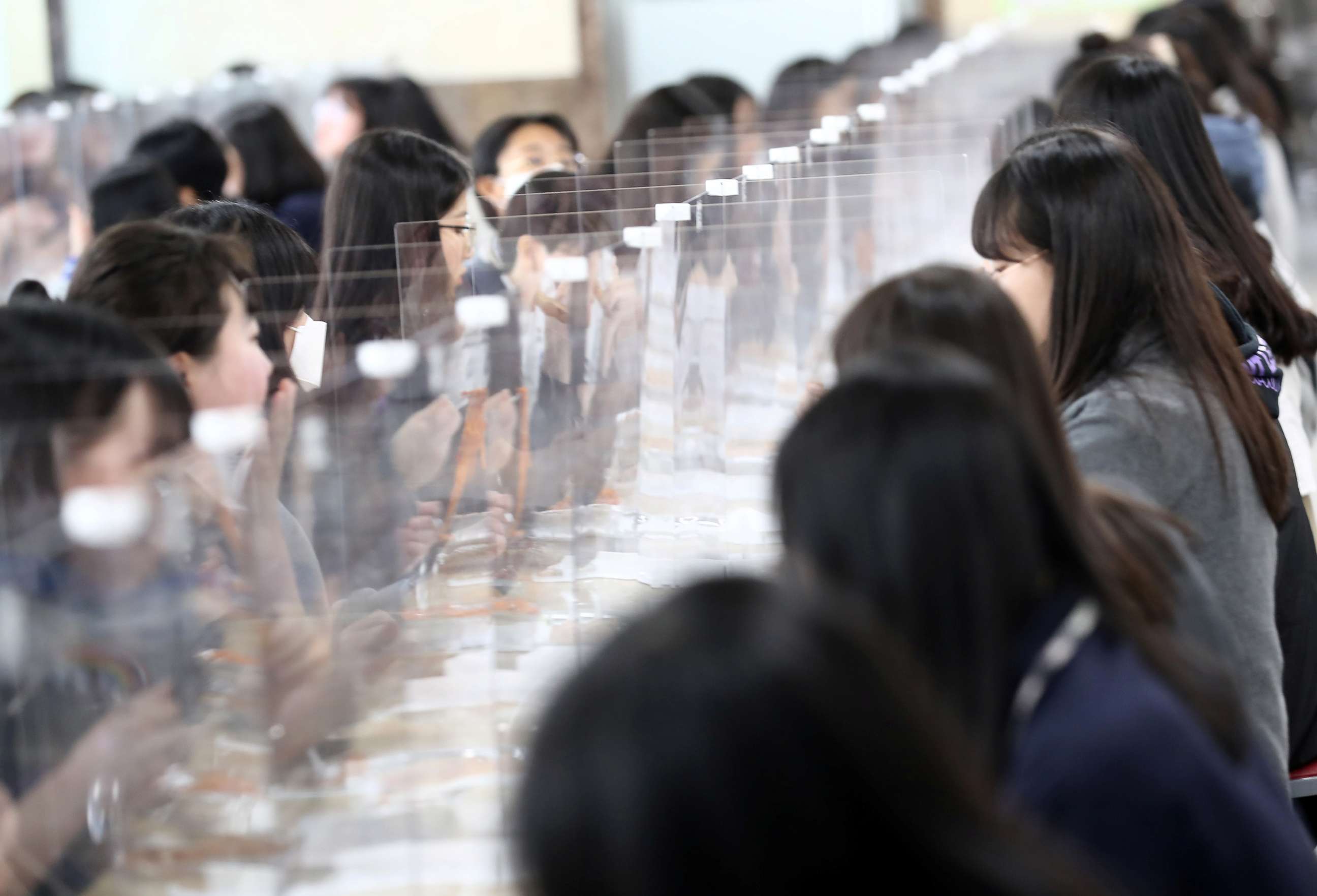 PHOTO: High school students eat lunch at a cafeteria with plastic screens on the table in Daejeon, South Korea, May 20, 2020.