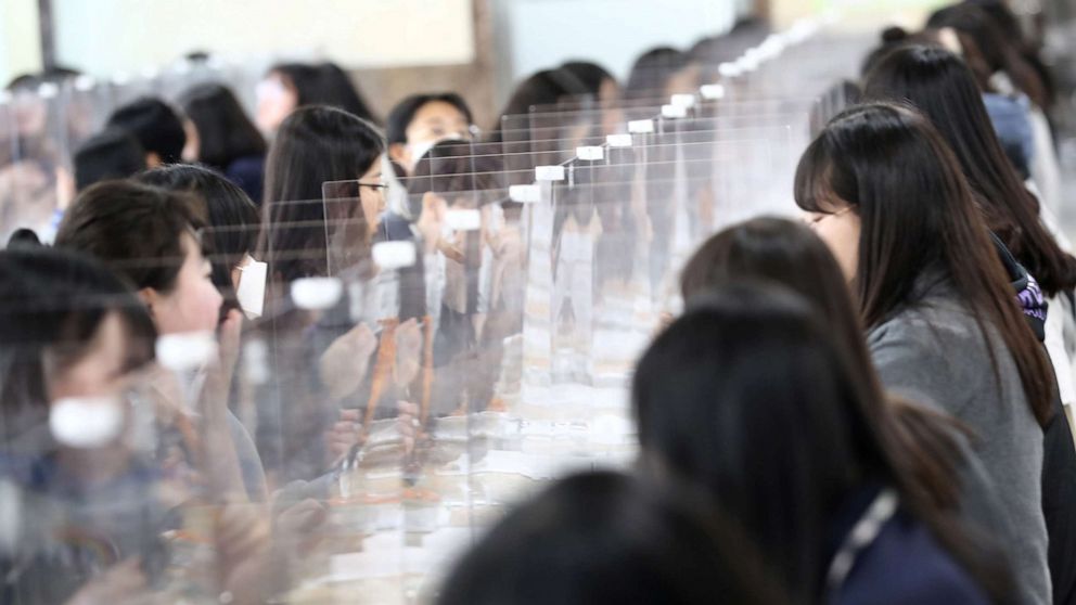 PHOTO: High school students eat lunch at a cafeteria with plastic screens on the table in Daejeon, South Korea, May 20, 2020.