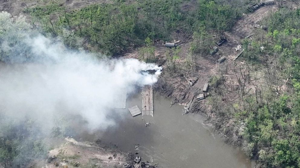 PHOTO: Smoke rises from what appears to be a makeshift bridge across the Siverskyi Donets River, eastern Ukraine, in this handout image uploaded on May 12, 2022.